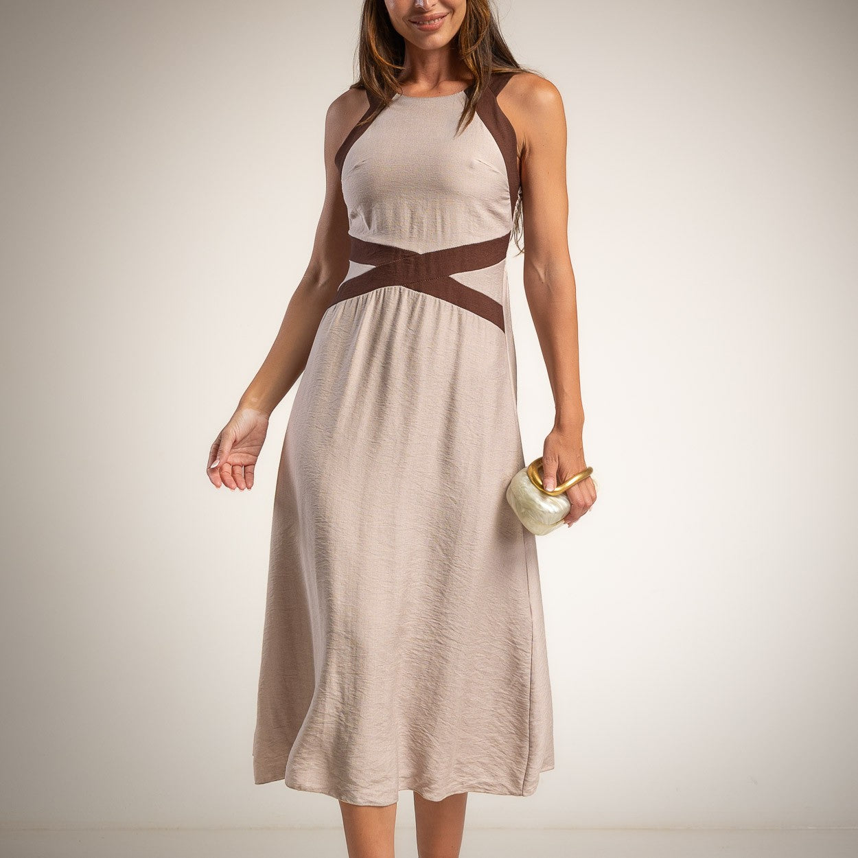 A woman wearing a sleeveless tape midi dress with brown crossover detail