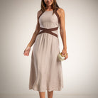 A woman wearing a sleeveless tape midi dress with brown crossover detail