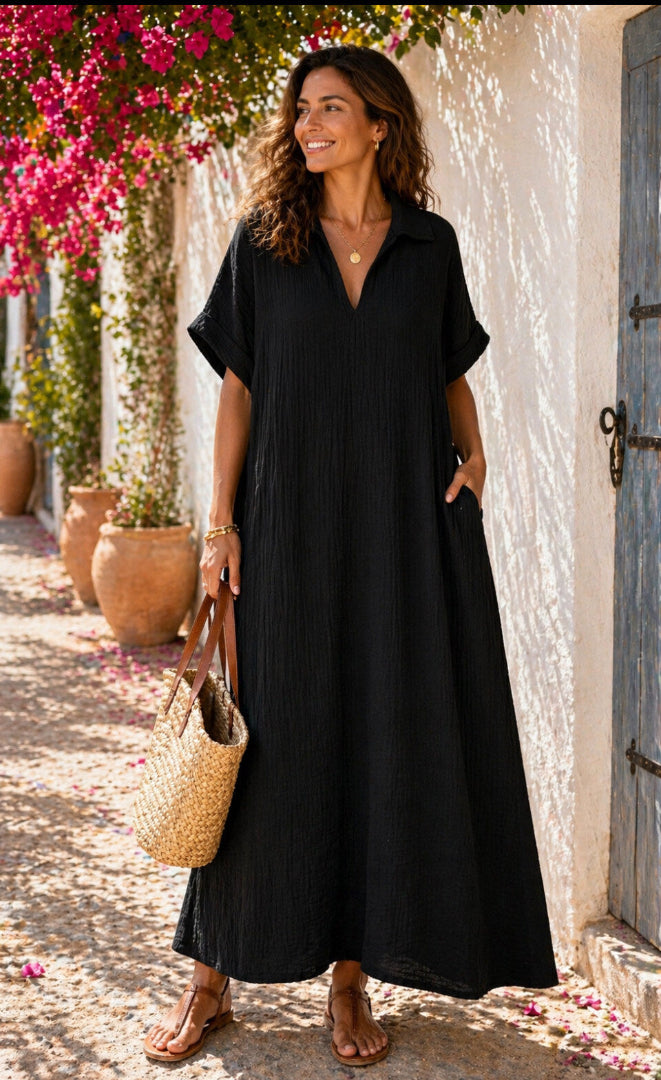 Woman in a black dress standing outdoors with flowers and a building in the background