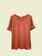 Orange t-shirt on a hanger against a neutral background