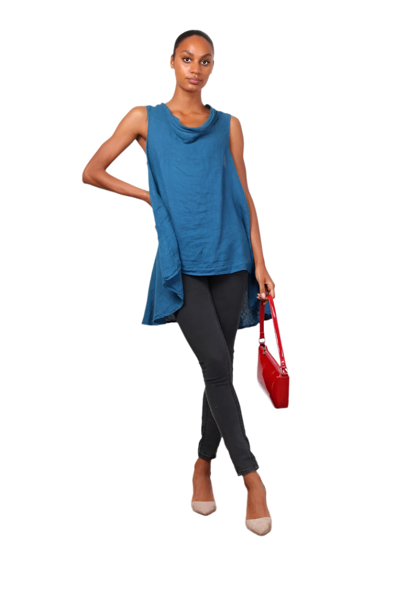 A woman wearing a duck egg blue sleeveless cowl neck top with an asymmetrical hem, paired with white trousers.