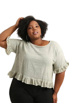 Woman wearing a duck green blouse with ruffled sleeves on a white background