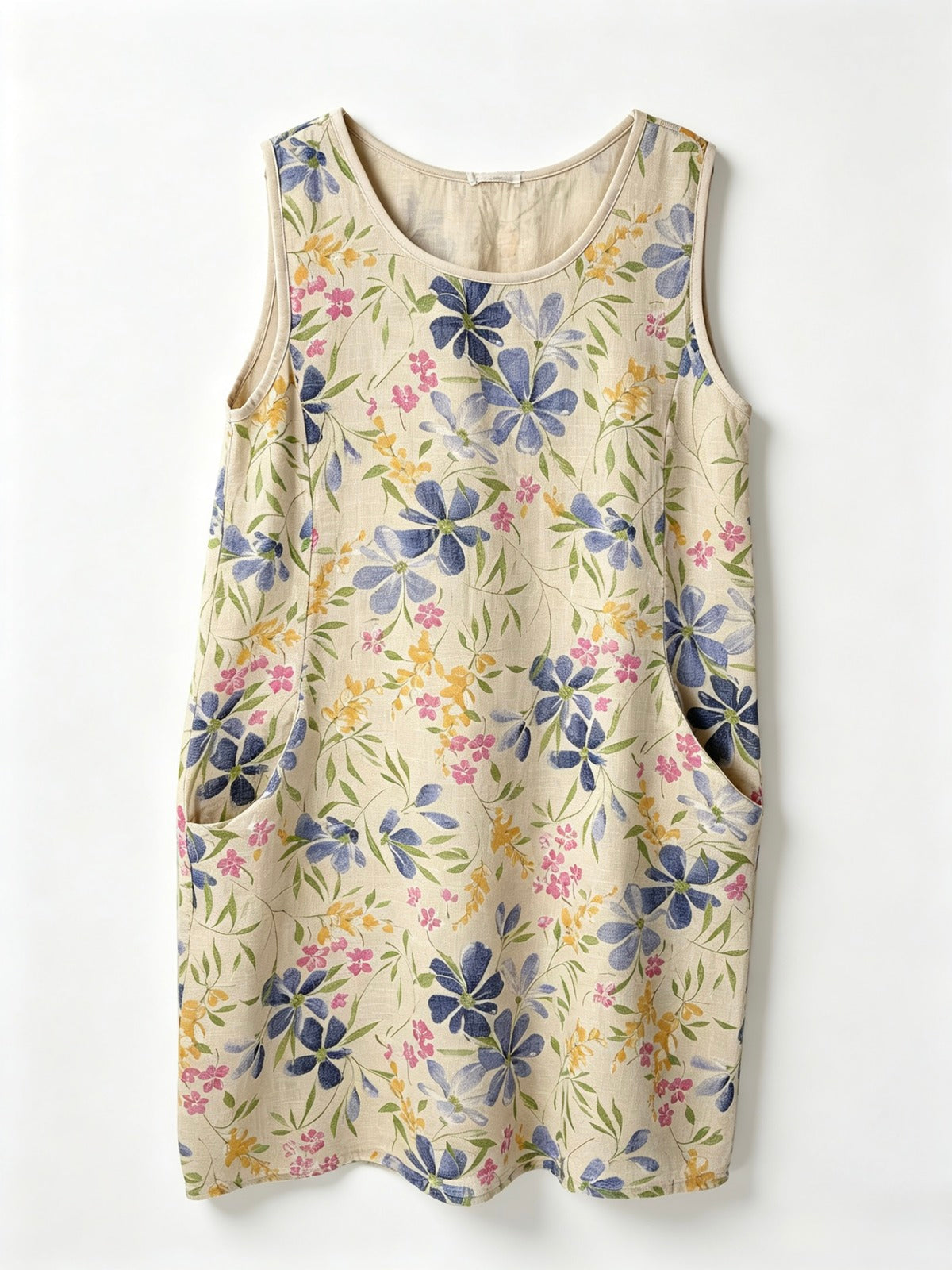 A sleeveless cream-colored dress with a blue, pink, and yellow floral pattern, featuring side pockets, shown against a plain white background.