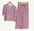 Pink polka dot outfit with top and pants on hangers against a white background