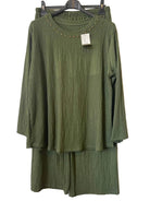 An olive green two-piece set consisting of a textured long-sleeve top with gold stud detailing around the neckline and matching textured pants,