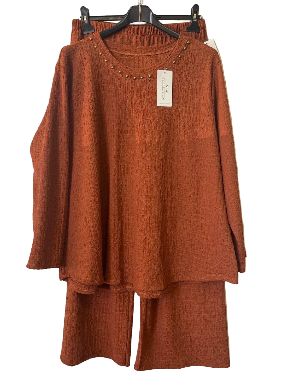 A rust-orange two-piece matching set consisting of a textured long-sleeve tunic top with a studded neckline and matching wide-leg pants