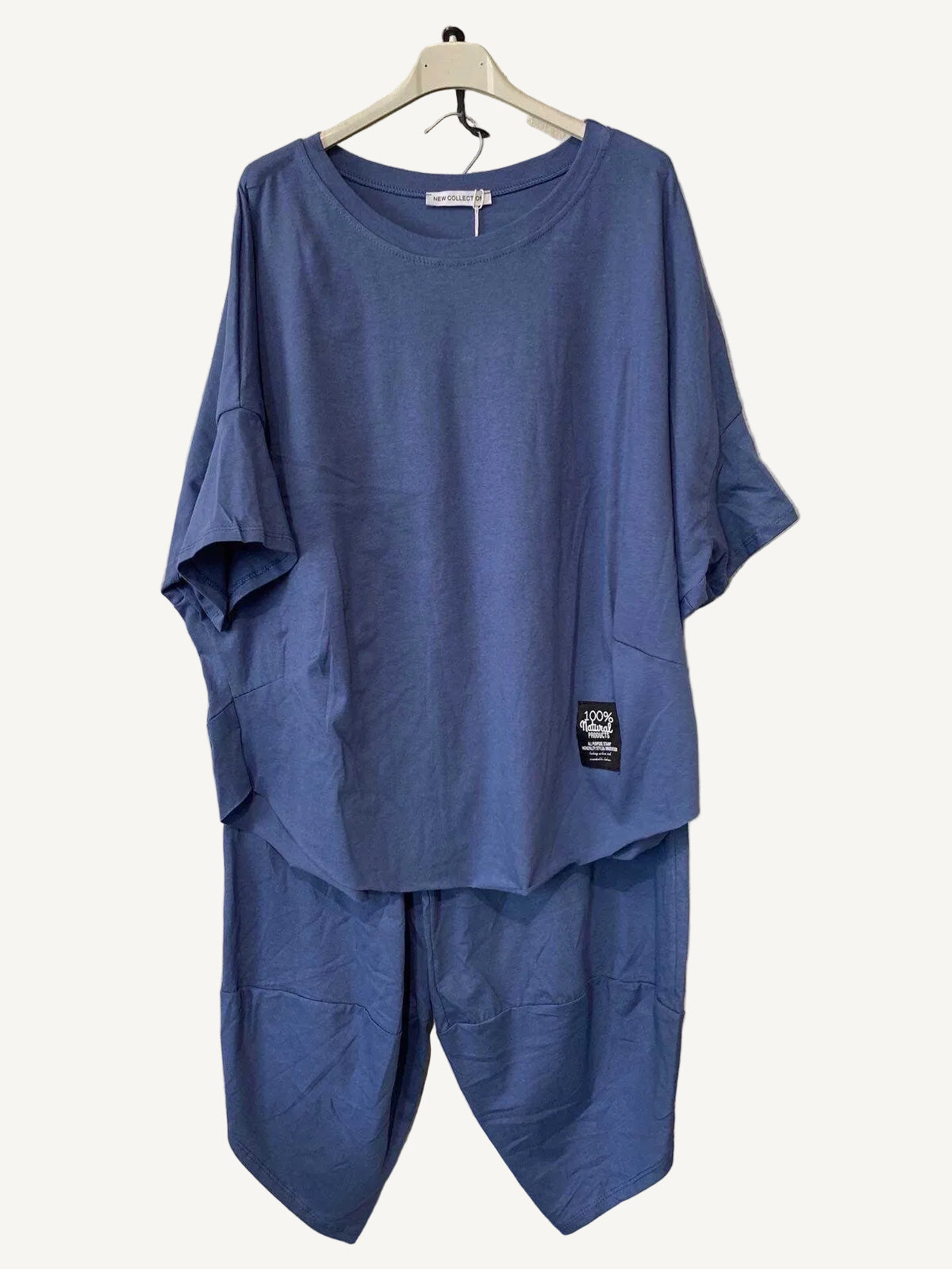 Blue outfit with a t-shirt and pants hanger against a textured wall.