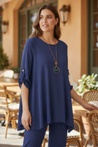Woman in a blue outfit standing outdoors with tables and chairs in the background