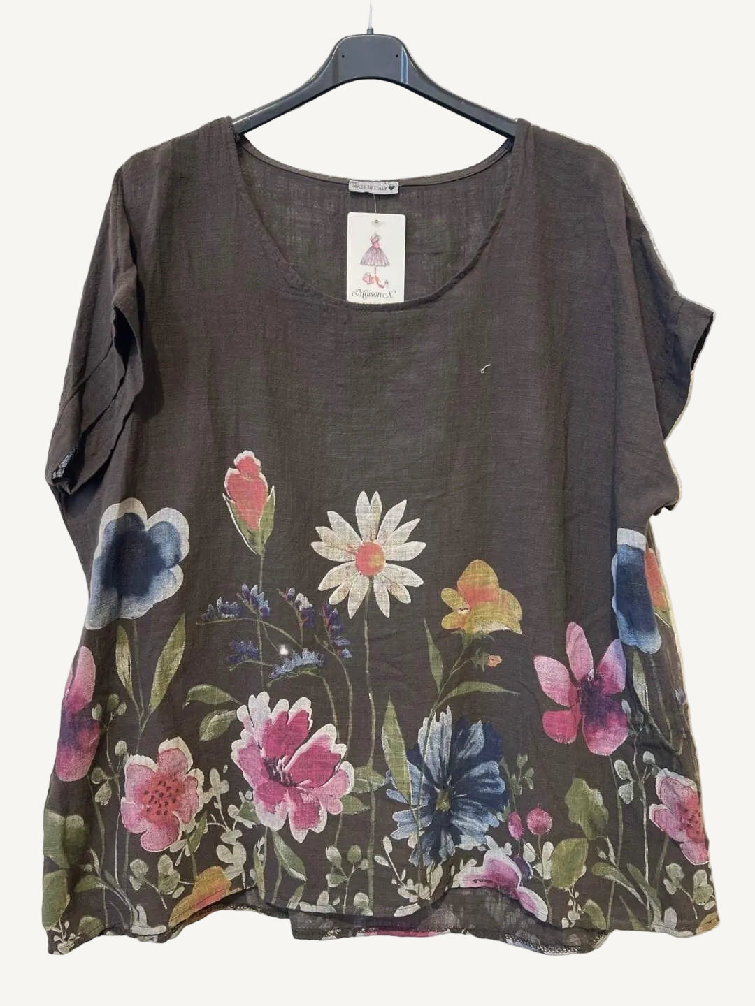 Floral-patterned brown top on a hanger against a textured white background
