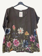 Floral-patterned brown top on a hanger against a textured white background