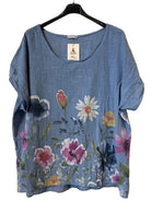 A women's short-sleeve top in blue jeans featuring a colorful floral print with pink, white, and yellow flowers.