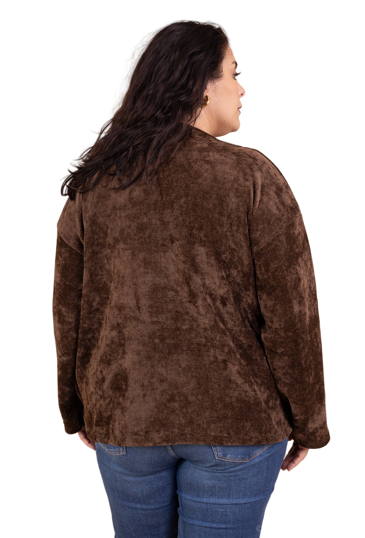 Person wearing a brown jacket and blue jeans against a beige background