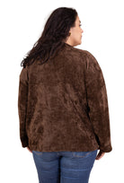 Person wearing a brown jacket and blue jeans against a beige background