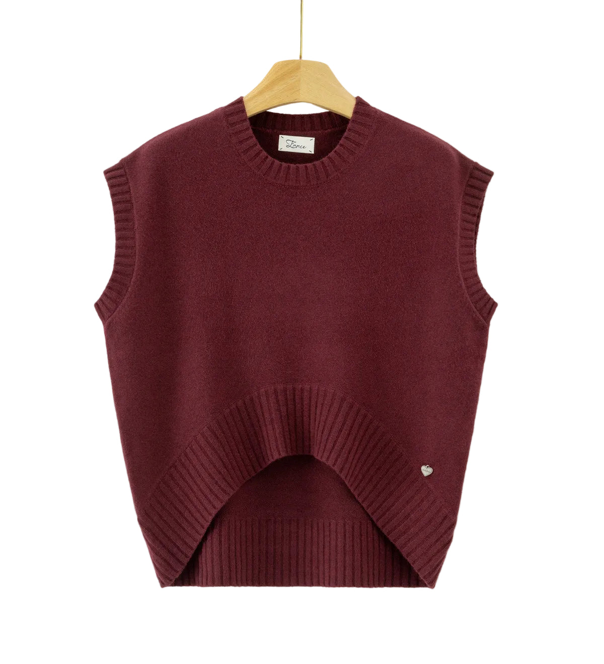 A sleeveless crewneck knit sweater vest in deep burgundy, hanging on a wooden hanger against a plain white background. The vest features a unique asymmetrical hem with a ribbed arch and a small silver heart detail on the lower right side.