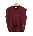 A sleeveless crewneck knit sweater vest in deep burgundy, hanging on a wooden hanger against a plain white background. The vest features a unique asymmetrical hem with a ribbed arch and a small silver heart detail on the lower right side.