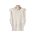 A sleeveless cream-colored knit sweater vest displayed on a wooden hanger against a light gray background