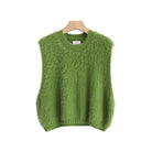 A green fuzzy knit sweater vest hanging on a wooden hanger against a light gray background,