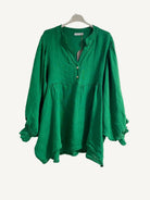 Green blouse on a hanger against a plain background