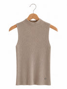 A sleeveless ribbed knit mock neck top in a light taupe-beige colour