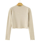 A beige ribbed knit long-sleeve crop top sweater hanging on a wooden hanger against a white background