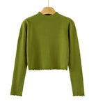 An olive green long-sleeve knit sweater with a cropped hem and scalloped edges, hanging on a wooden hanger against a plain white background. 
