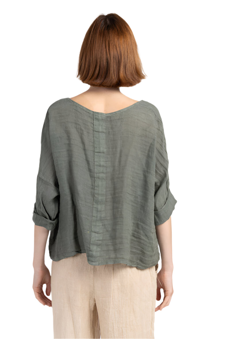 Person wearing a khaki blouse with rolled-up sleeves on a white background