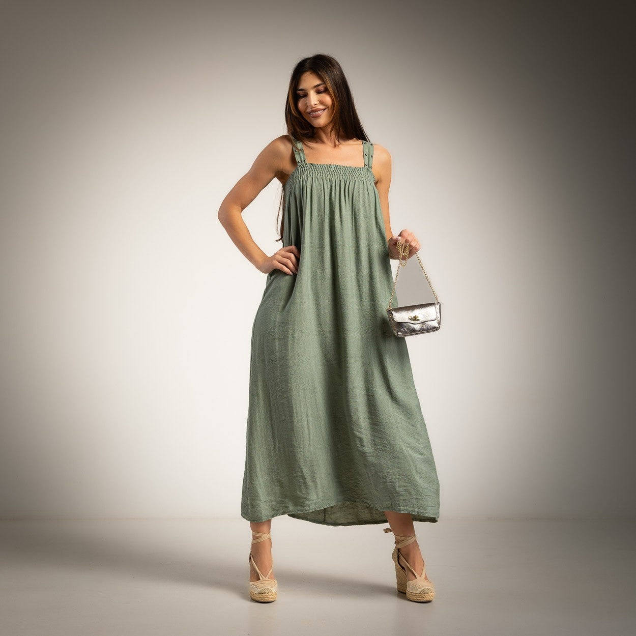A woman modeling a green maxi dress with a smocked bodice and studded straps