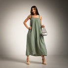 A woman modeling a green maxi dress with a smocked bodice and studded straps