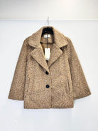 A textured beige tweed coat with a double-breasted design, hanging on a black hanger against a plain white wall.