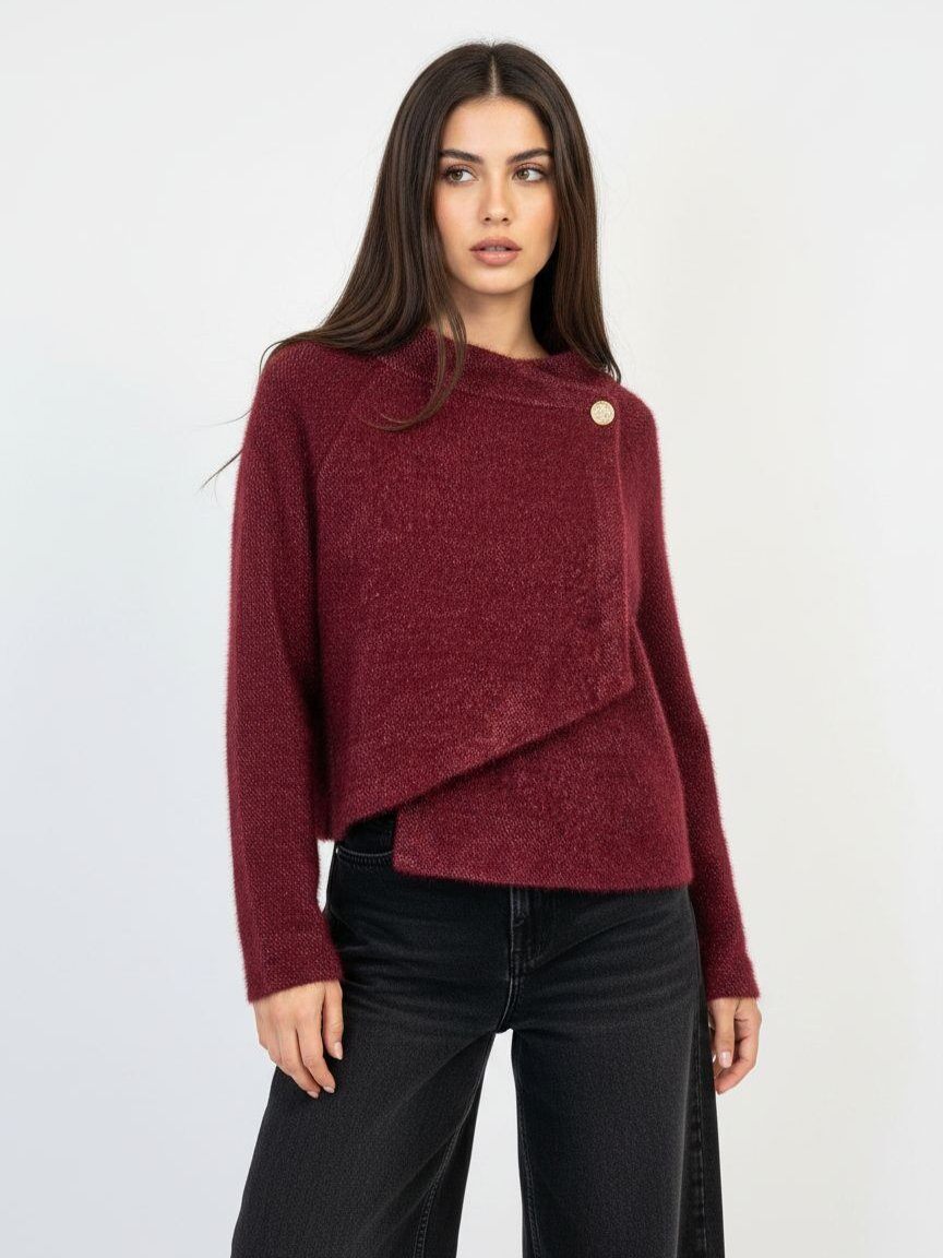 A woman modeling a textured, off-the-shoulder burgundy knit sweater with a single gold button detail, paired with black jeans, against a plain white studio background.