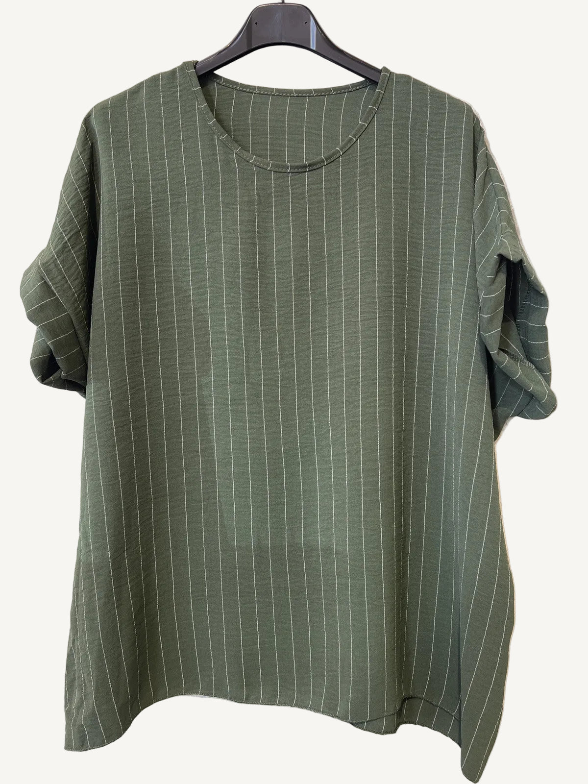 Green striped shirt on a hanger against a textured white background