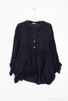 navy blouse on a hanger against a white background