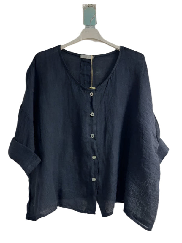 A woman wearing a navy blue one size pure linen button fronted collarless shirt with three quarter sleeves.