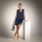 A woman models a navy blue sleeveless top and matching shorts set with beige lace-up sandals
