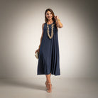 A woman modeling a sleeveless navy blue midi dress with a flowing silhouette. 