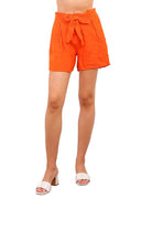 Person wearing bright orange shorts with a tie waist on a white background