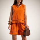 A woman models a bright orange sleeveless top with matching shorts