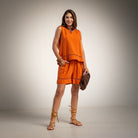 A woman modeling a bright orange sleeveless tunic and matching shorts set,