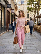 Woman walking down a street in an urban setting, holding a coffee cup and shopping bag.