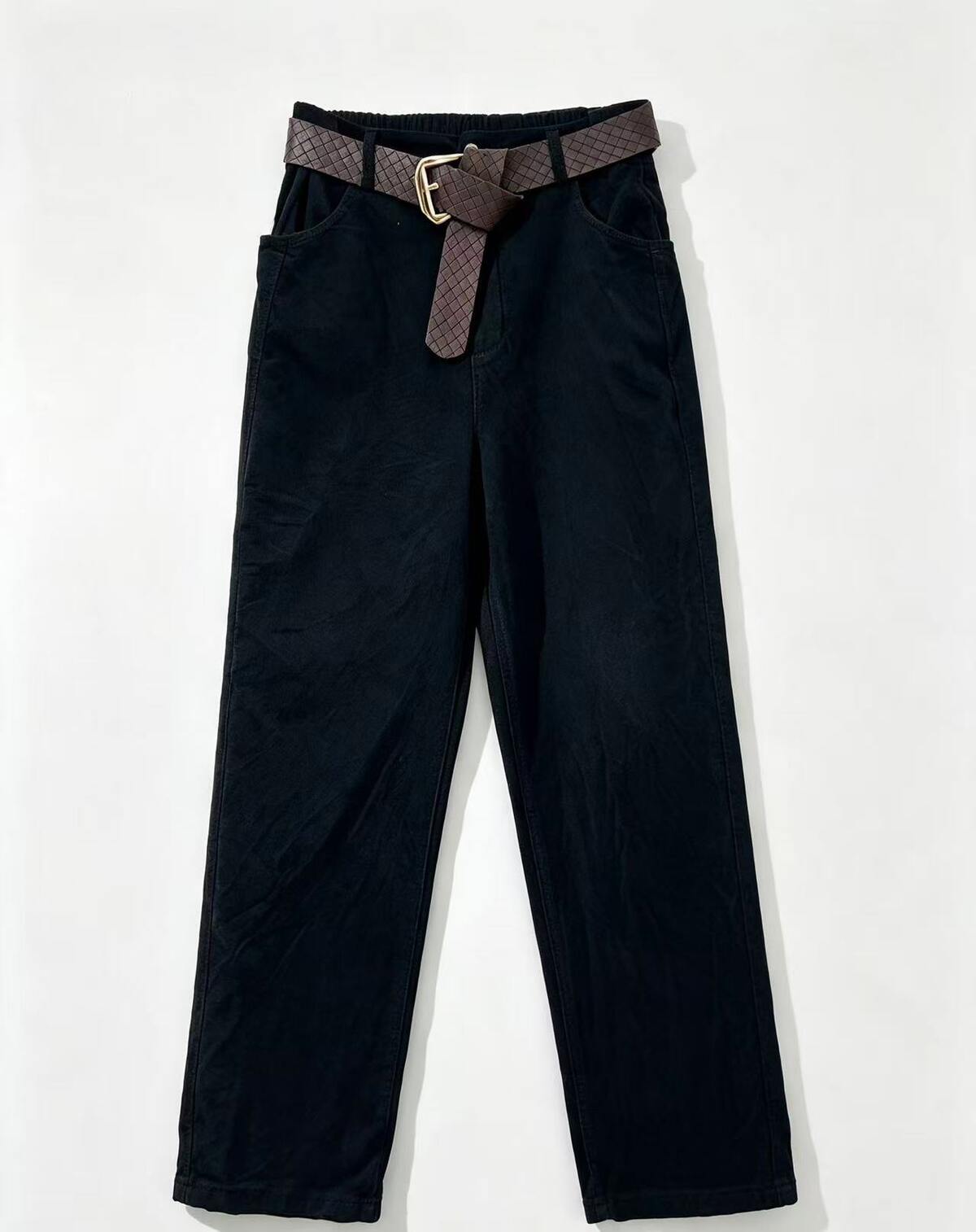 Black corduroy pants with a brown patterned woven belt featuring a gold buckle, displayed flat against a white background.