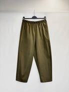Olive green wide-leg cropped pants with an elastic waistband, hanging on a black hanger against a white backdrop.