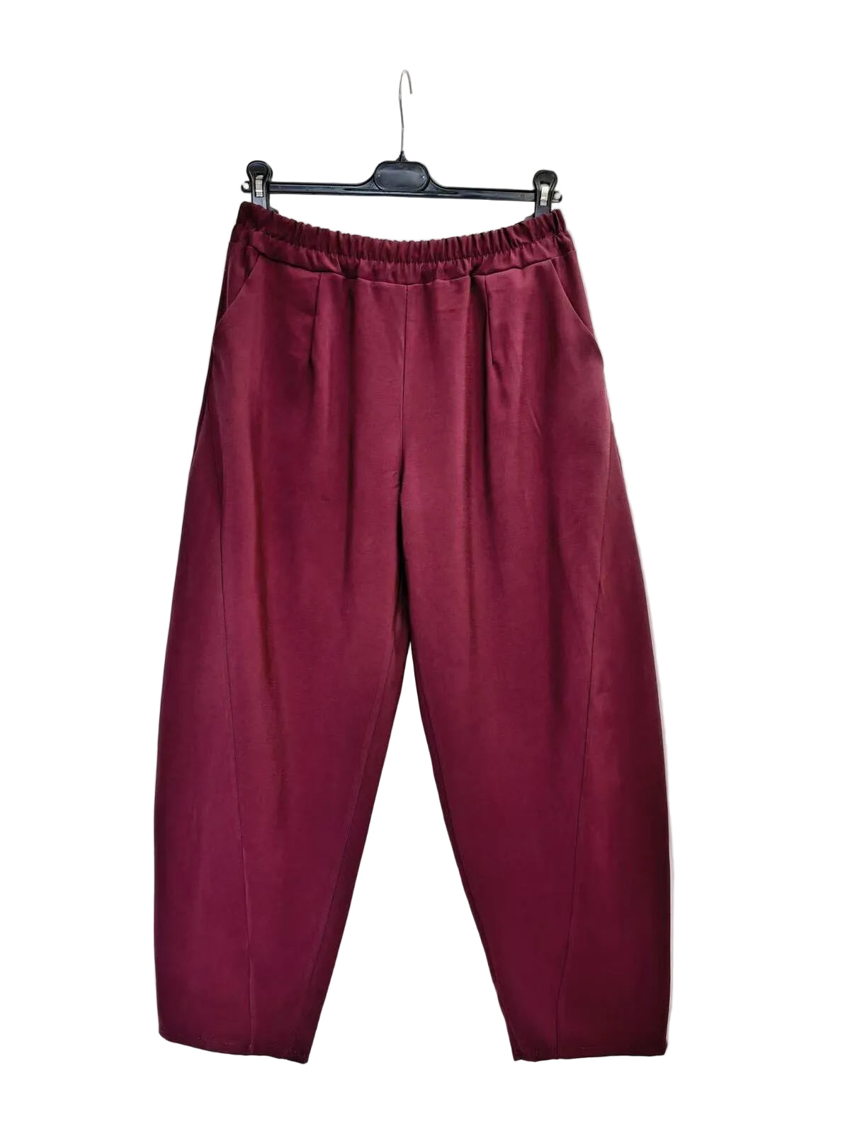 A pair of loose-fitting, pleated trousers in a deep burgundy or maroon color, hanging from a black hanger against a plain white backdrop.
