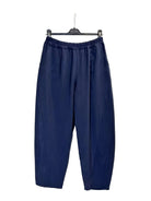 A pair of navy blue cropped pants with an elastic waistband, hanging from a black hanger against a plain white backdrop.