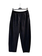 Black wide-leg cropped pants with an elastic waistband, hanging on a black hanger against a plain white wall.