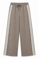 A pair of wide-leg sweatpants in taupe with three white stripes running down the sides, featuring an elastic waistband and a matching drawstring.