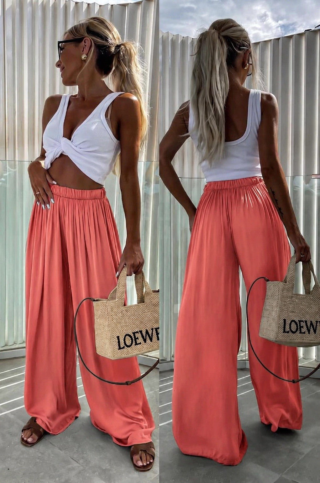 A woman shown from the front and back wearing a white twisted-strap crop top and flowing coral wide-leg pants, standing outdoors against a corrugated metal wall and holding a woven Loewe tote bag.
