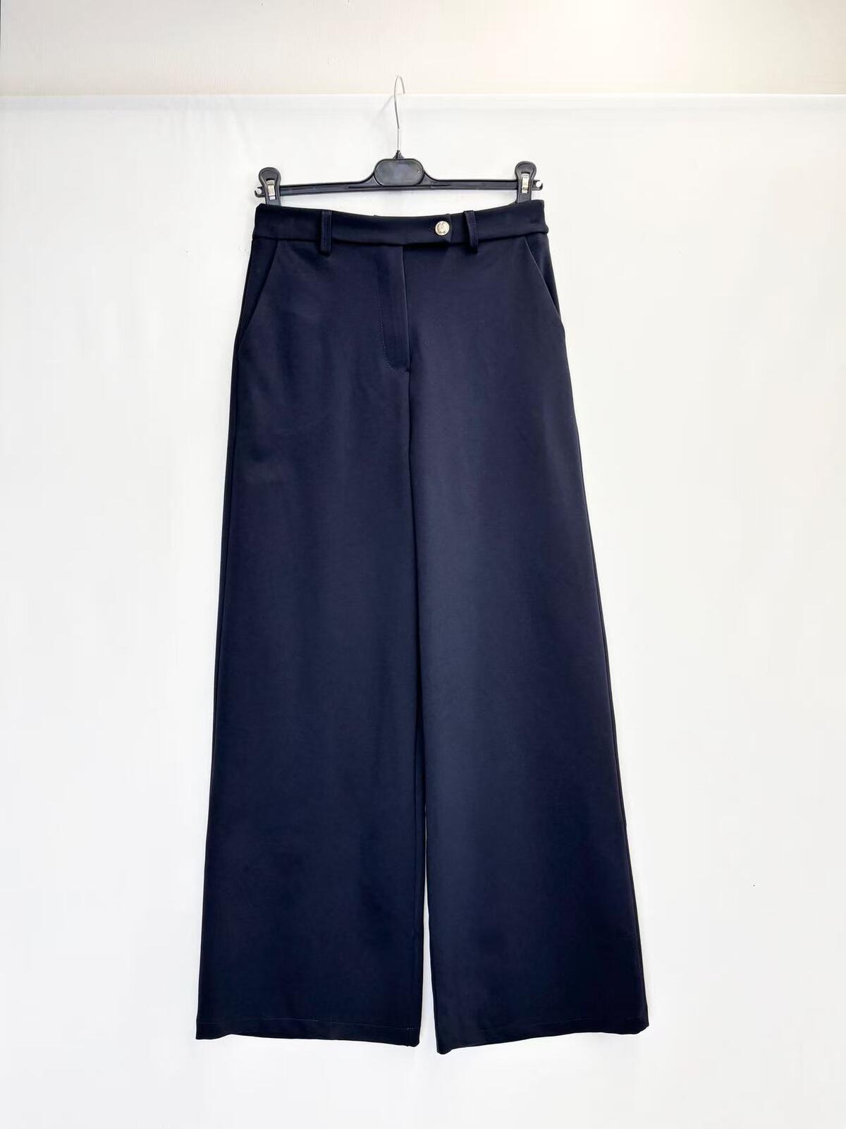 A pair of dark navy blue trousers hanging on a black hanger against a plain white background.