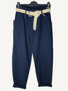 Navy blue pants with a beige belt on a textured white background