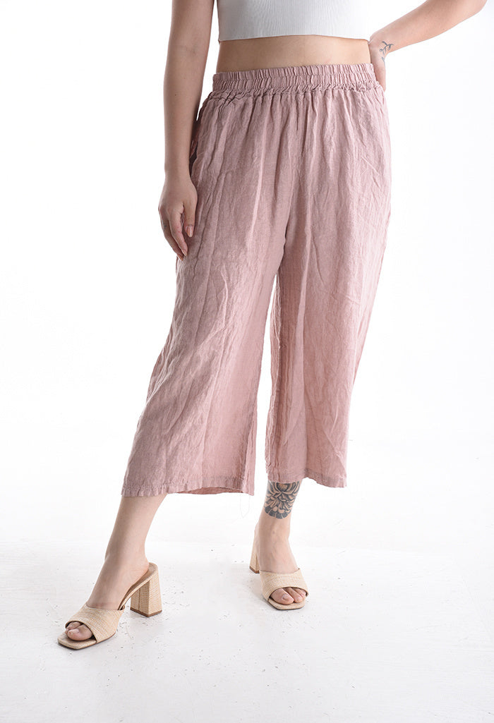 Person wearing light pink wide-leg pants on a white background