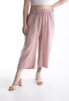 Person wearing light pink wide-leg pants on a white background